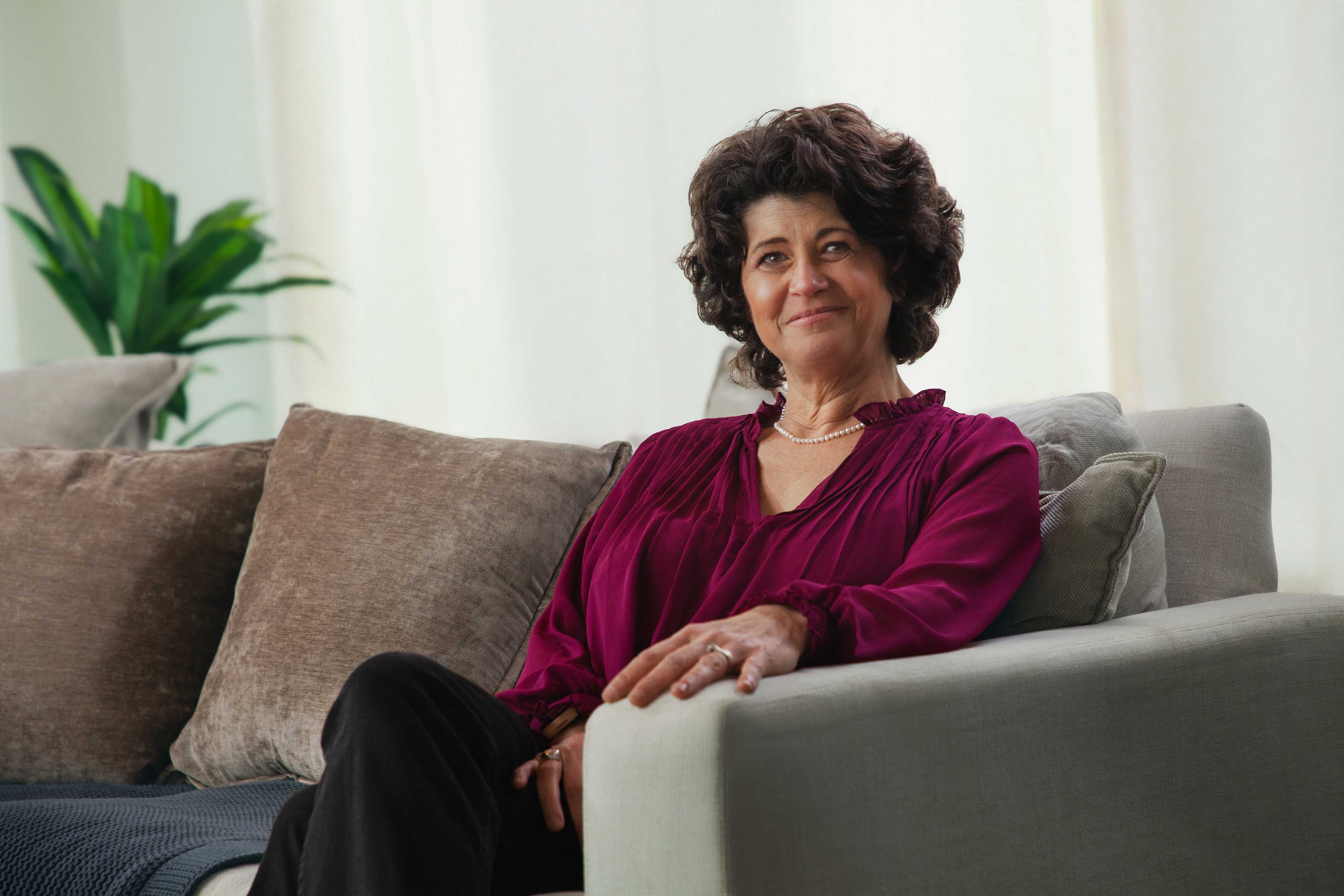 brunette woman sitting on couch smiling